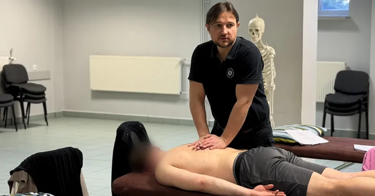 Physiotherapist examining the lower back of a patient lying prone