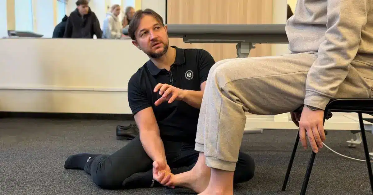 Physiotherapist assessing lower limb spasticity in a seated patient during a clinical course